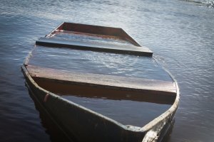 een bootje dat vol met water staat. Het zinkt nog net niet.