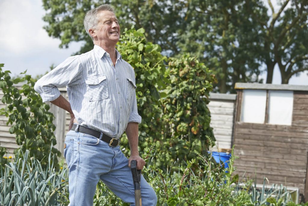 man aan het spitten in de tuin.